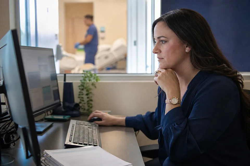 Hospital IT security engineer reviewing a held request at her desk
